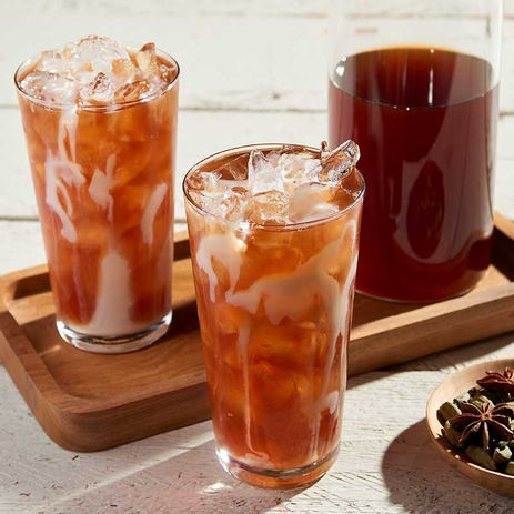 A trio of iced tea drinks with a swirl of cream, styled with warm tones and natural lighting.