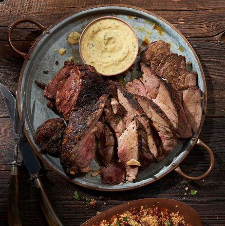 Plate of sliced beef served with dipping mustard sauce on a rustic table