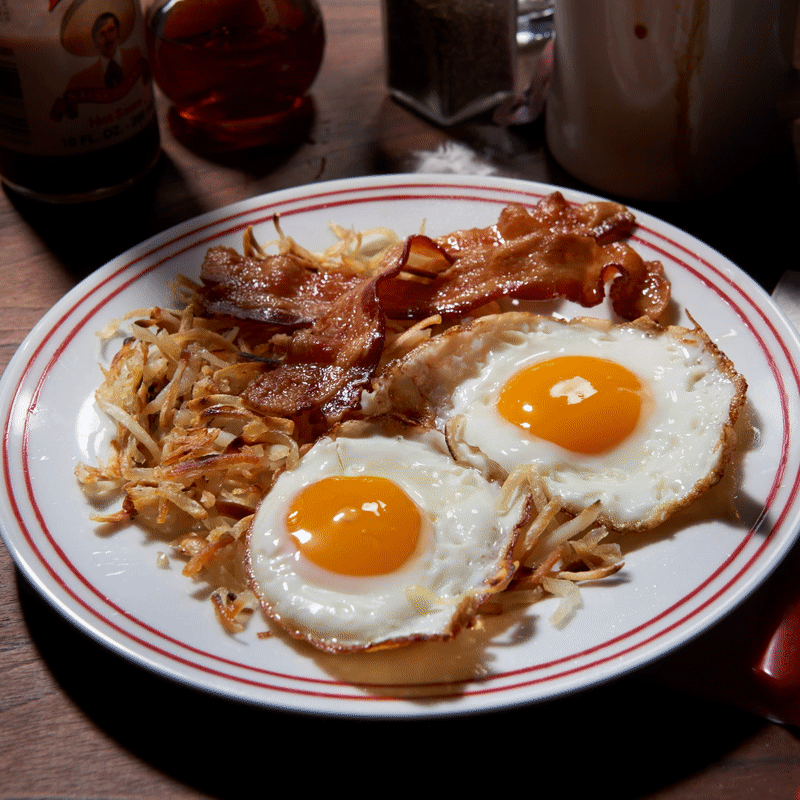 Messy breakfast plate gif with fried eggs and scattered food remnants on a diner-style dish