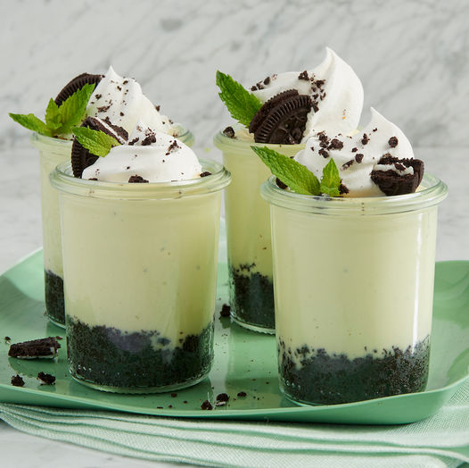 Small dessert cups filled with cookies and cream parfait topped with whipped cream and mint