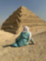 Woman in a dress sitting in front of a pyramid in Egypt