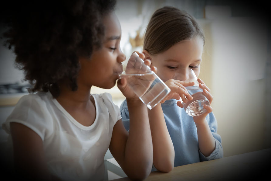 Two children drinking glasses of water