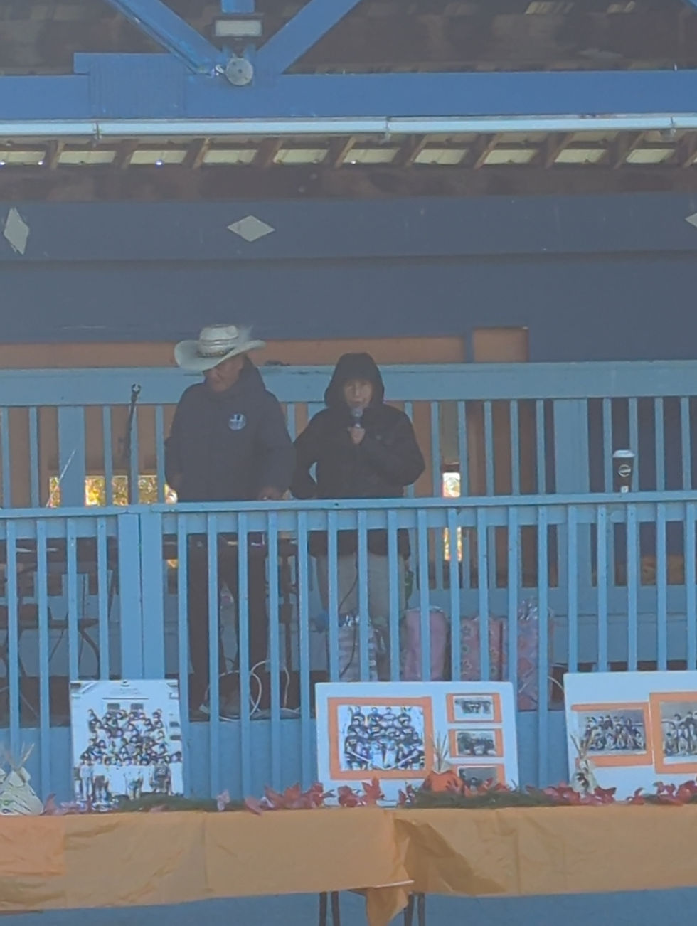 Eye-level view of a microphone standing near orange shirts during a community remembrance event.