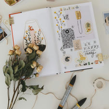 Creative art journal with dried flowers and sketches.
