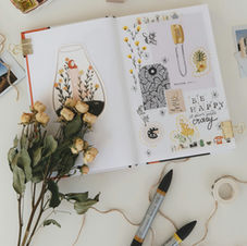 Creative art journal with dried flowers and sketches.
