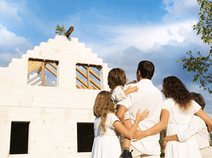 Family standing together in front of a partially rebuilt home, symbolizing hope and resilience during the California wildfire rebuilding process with a trusted home builder.