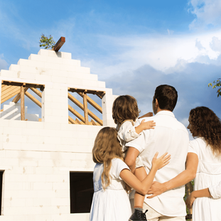 Family standing together in front of a partially rebuilt home, symbolizing hope and resilience during the California wildfire rebuilding process with a trusted home builder.
