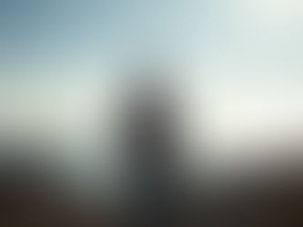 A homeowner standing at the edge of a wildfire-scarred lot in Pacific Palisades, looking out over the ocean. The scene should convey contrast - emotional weight and destruction on one side, optimism and transformation. | Monument Home Builders