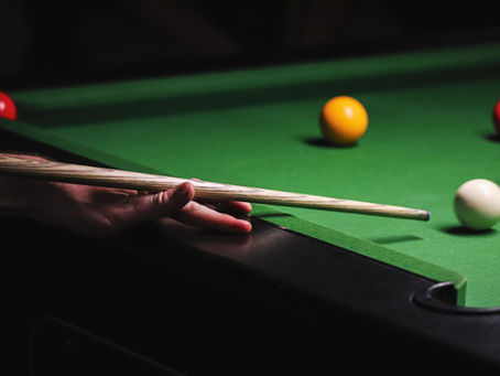 Hand playing billiards on a green table