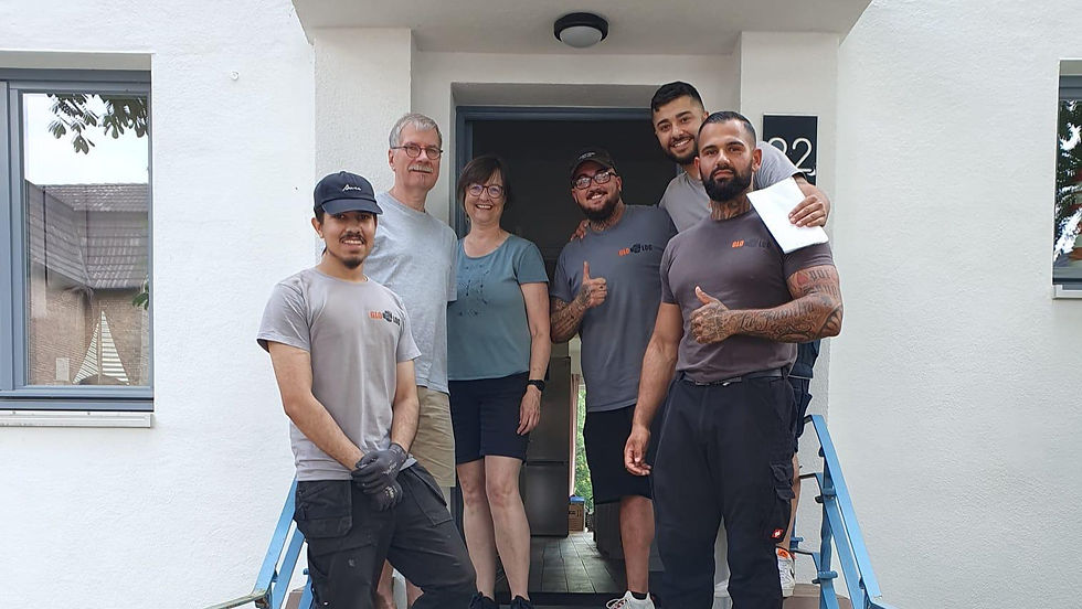 GLOLOG Team mit zufriedenen Kunden nach einem Umzug in Hannover vor der Haustür des neuen Zuhauses