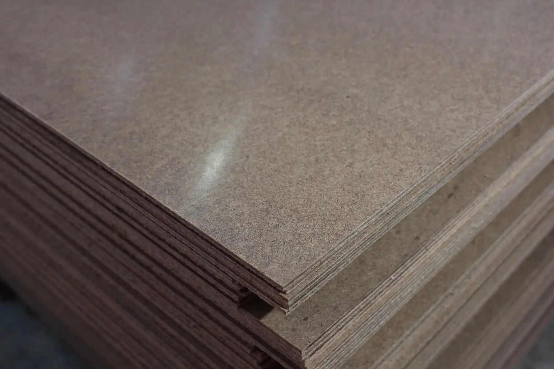 Close-up of finished hardboard sheets showing the smooth face and dense edges