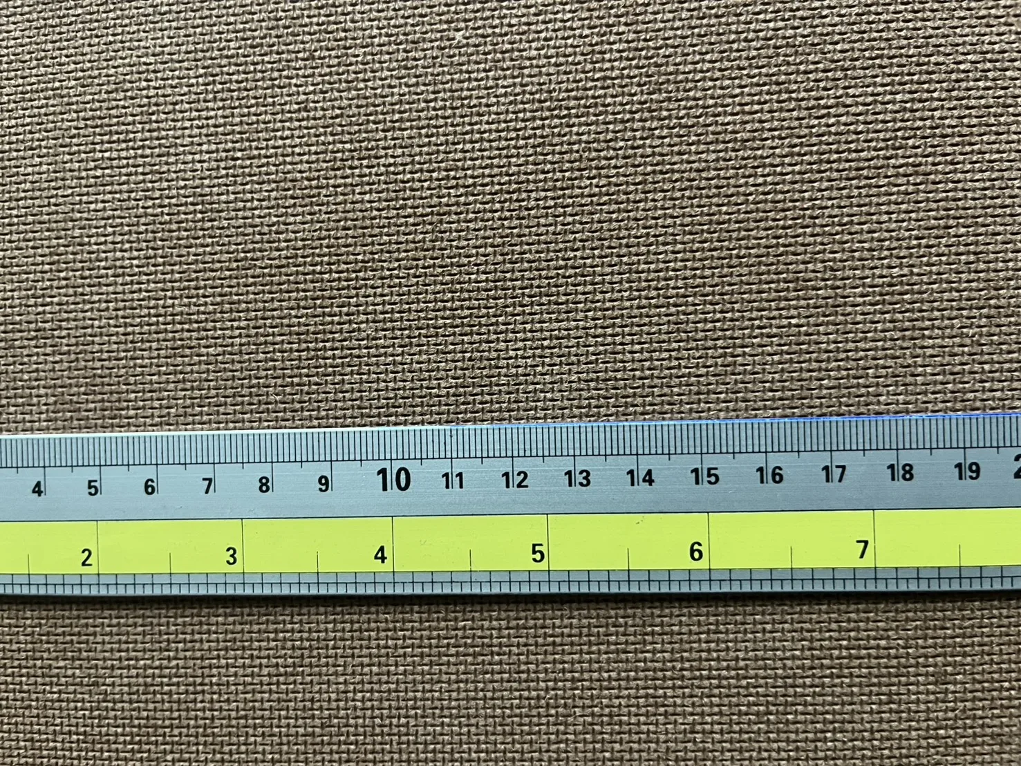 Mesh-pattern hardboard surface shown with a measuring scale for visual reference