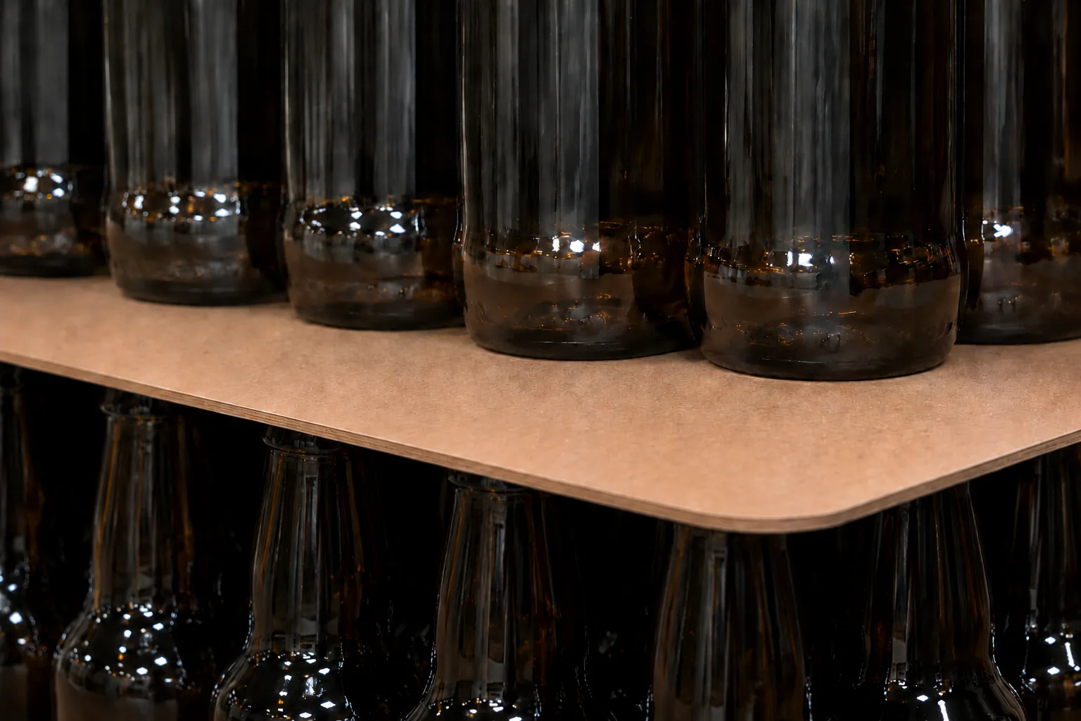 Close-up of a hardboard layer pad between two tiers of glass bottles