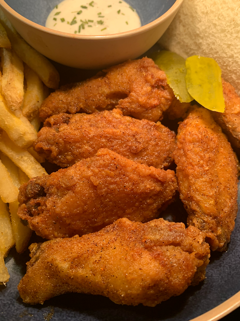 Nashville hot wings with french fries, bread, pickles, and a side of ranch dressing.