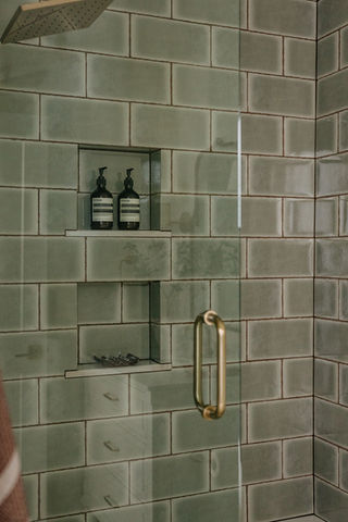 Sage tile shower surround with brass fixtures — Birmingham Michigan primary bathroom remodel by Costello & Co