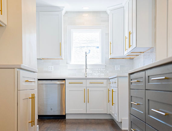 Classic kitchen design with white cabinetry, gold hardware, and a blend of white and gray cabinets for contrast.