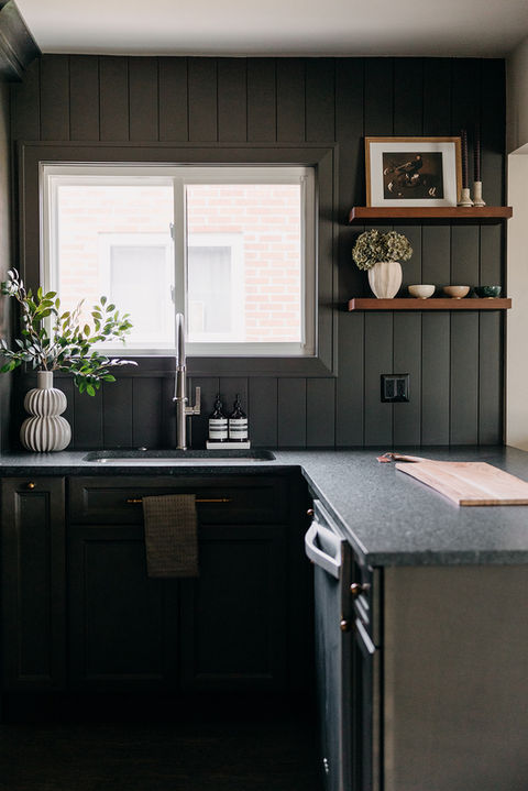 Modern black kitchen cabinetry with wood accents and stainless appliances 