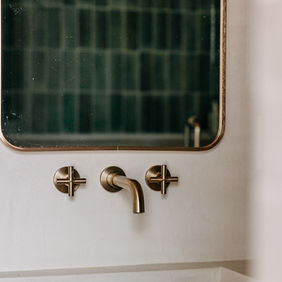 Mirror and brass wall-mount faucet close-up
Brass wall-mount faucet with arched mirror — Royal Oak Michigan primary suite bathroom by Costello & Co Construction