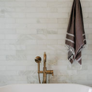 Brass tub filler and towel with marble background Floor-mounted brass tub filler beside freestanding tub — Bloomfield Hills Michigan primary bathroom by Costello & Co Construction