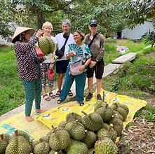 Tourists experiencing durian fruit tasting at local Mekong Delta farm during Saigon Happy Tour authentic cultural adventure