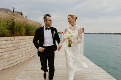 bride and groom holding heads running along the lake on their wedding day
