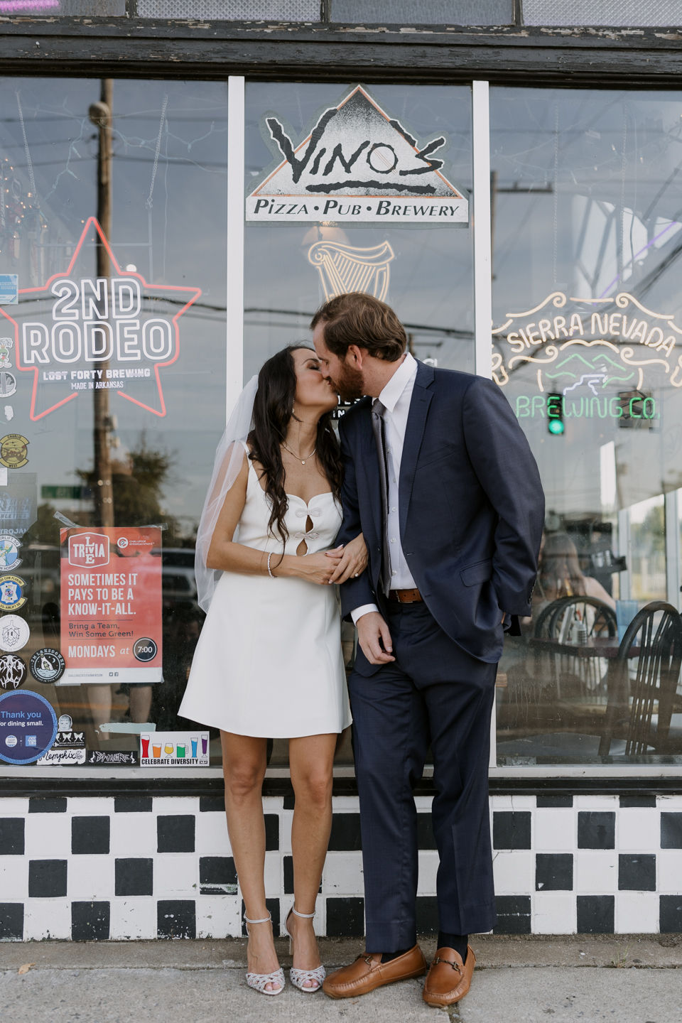 couple stand in front of vinos pizza and brewery