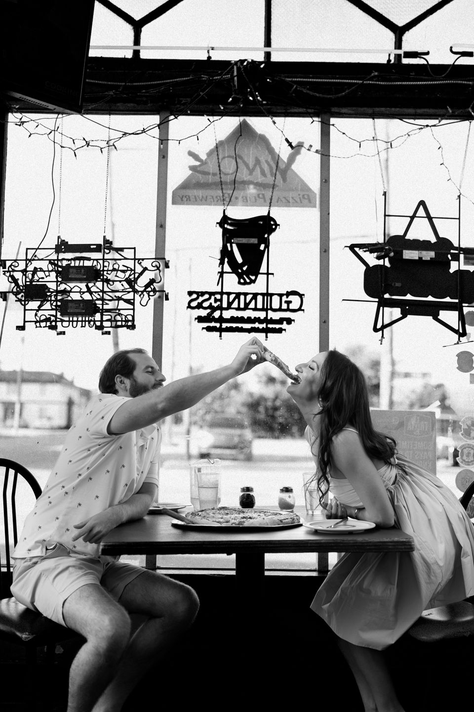 engagement photo couple sitting feeding each other pizza