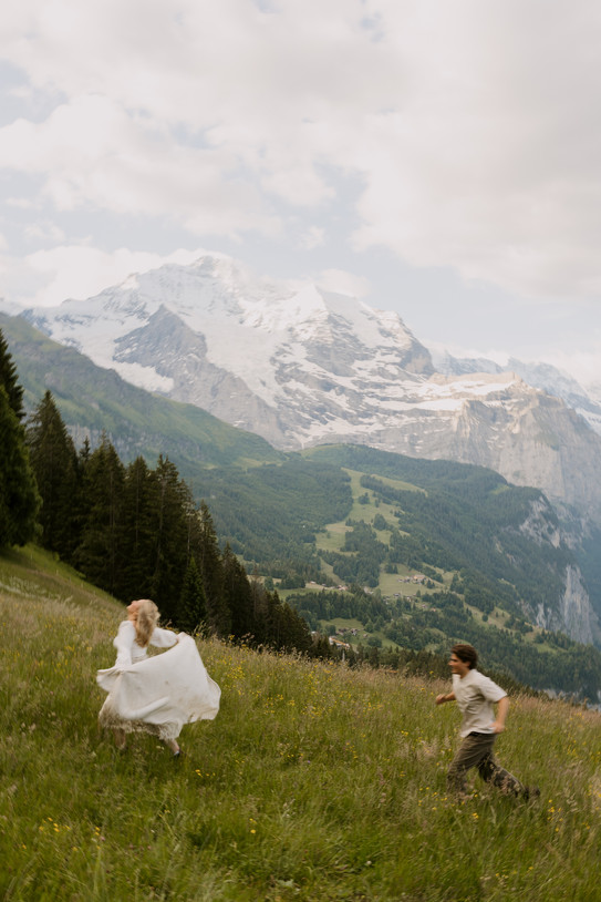 couple running through a field on top of a mountain in Switzerland