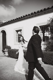 black and white photo of bride and groom running, bride looking back at her husband, location is a european cibe