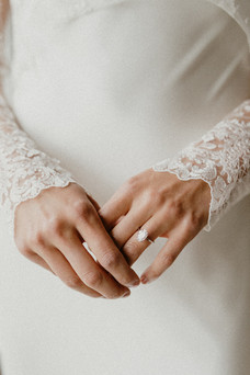 bride holds her ring with lace sleeves