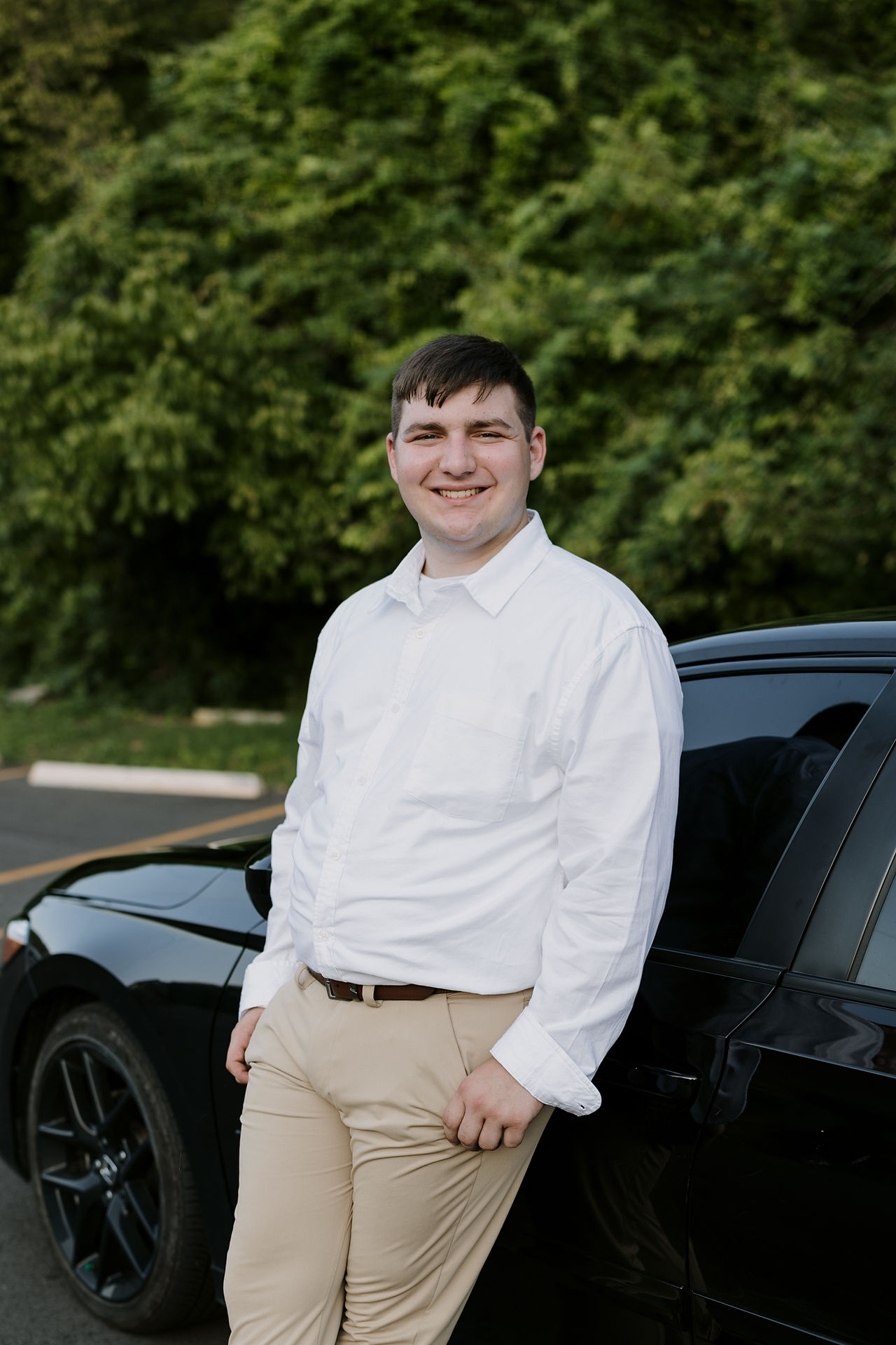 senior photo guy standing by his car