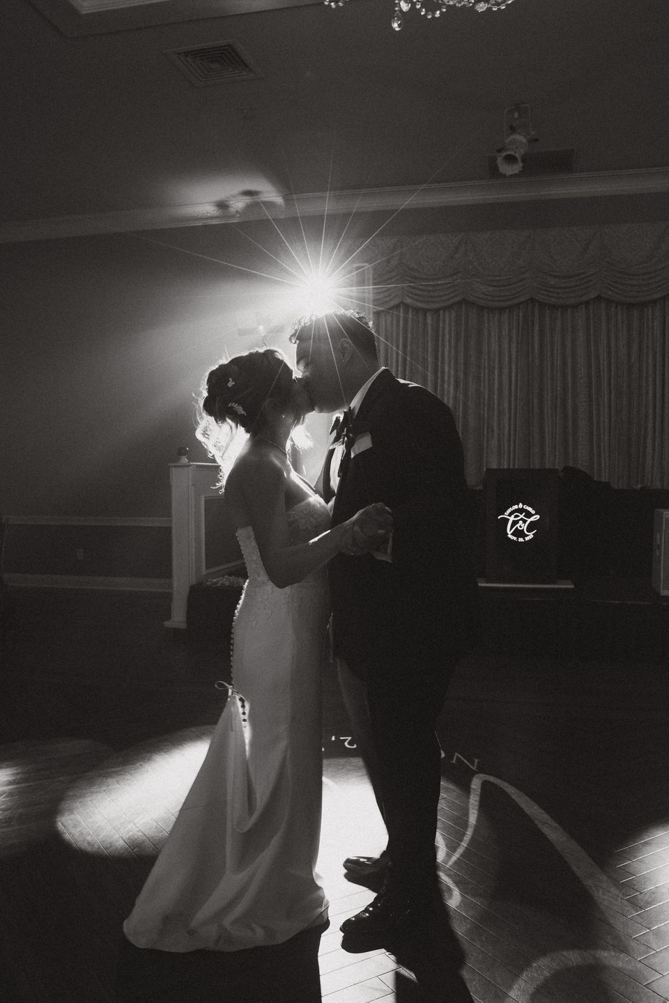 newlyweds kiss on the dance floor with the party lights surrounding them