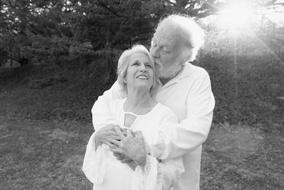 older couple photoshoot, grandma and grandpa embrace with sunset in the background
