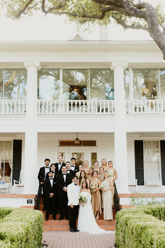 wedding party stands on the steps in front of beautiful wedding venue in Texas