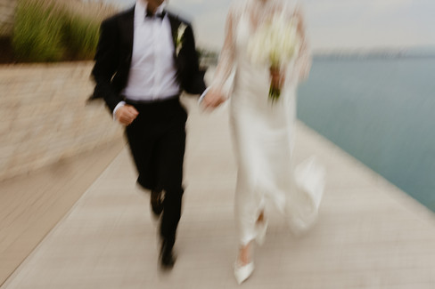 newlywed bride and groom running on the dock by the lake. blurry photo, full of emotion