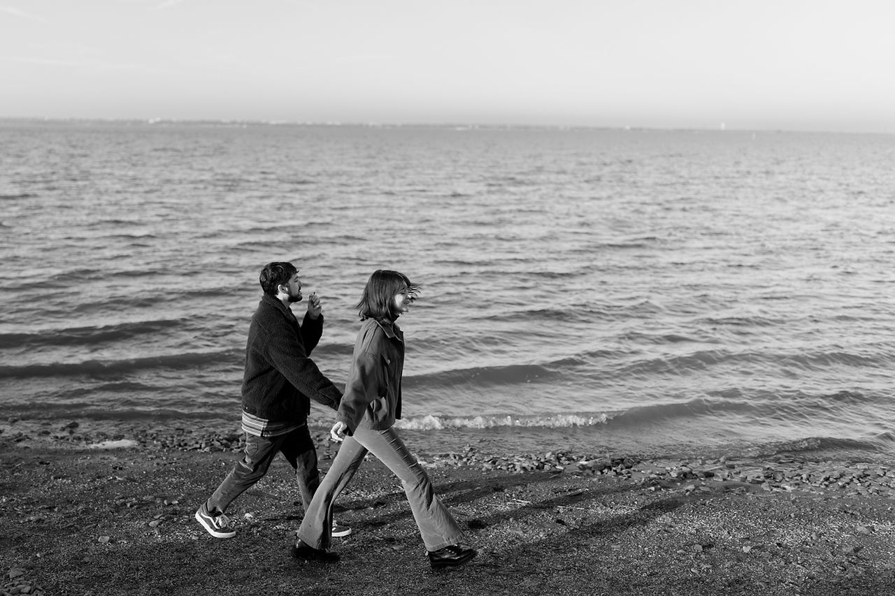 couple walk smoking a joint by the lake engagement photos