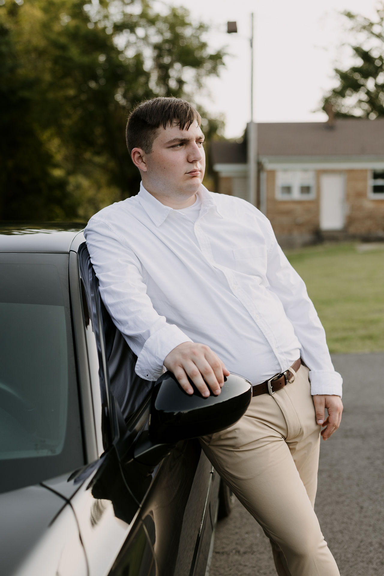 senior photo guy standing by his car
