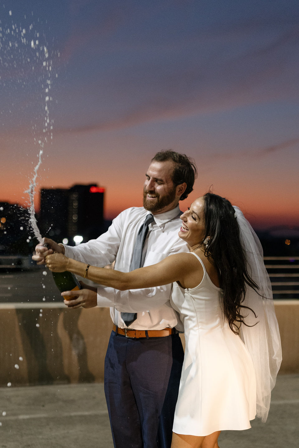 downtown engagement couple popping champagne