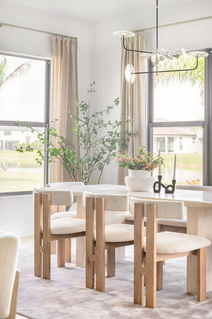Dinning area room with table and chairs a beige carpet with curtains and a plant on the side of the room.