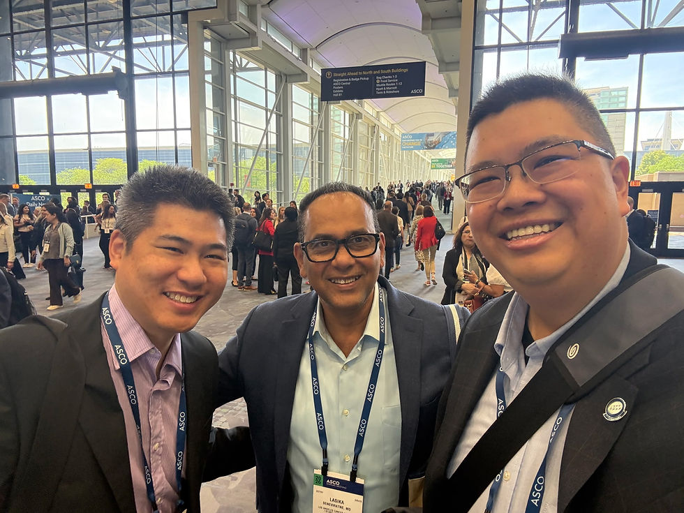 Three smiling men in suits take a selfie at an ASCO conference hall, with crowds and directional signs in the background.