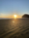 The image is a photo I took while walking onto North Piha Beach, on the West Coast of Auckland, New Zealand. It is a crisp early autumn day, the sun is nearly setting and is shining golden between some fluffy clouds onto the ocean and the beach. There is one couple walking side by side in the far distance, and another individual by themselves. When I look at the picture I see beauty and warmth, I feel connected and grounded and not alone. I get the sense, from all the foot prints on the sand, that even though my journey is my own, I am not alone in it.