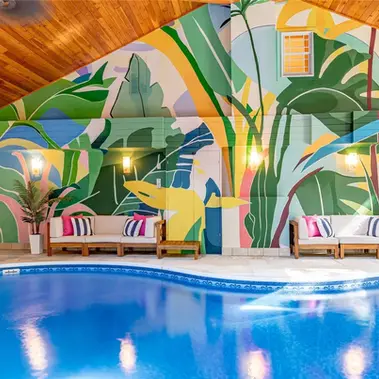 Residential hospitality amenities, indoor pool mural, large floral natural mural with leaves and shadows creating a tropical ambience. Dramatic interior large scale artwork painted by Marshall Okin of Art Etc. Indoor pool and bar. Relaxing atmosphere created by large wall art designed and created by Marshall Okin for a luxury residence Airbnb.