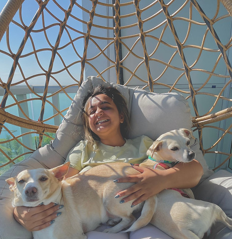 Karishma with two small dogs sitting on a swing, in the sun