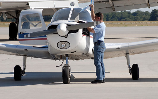 Aircraft mechanic performing prebuy inspection on light aircraft engine and cowling