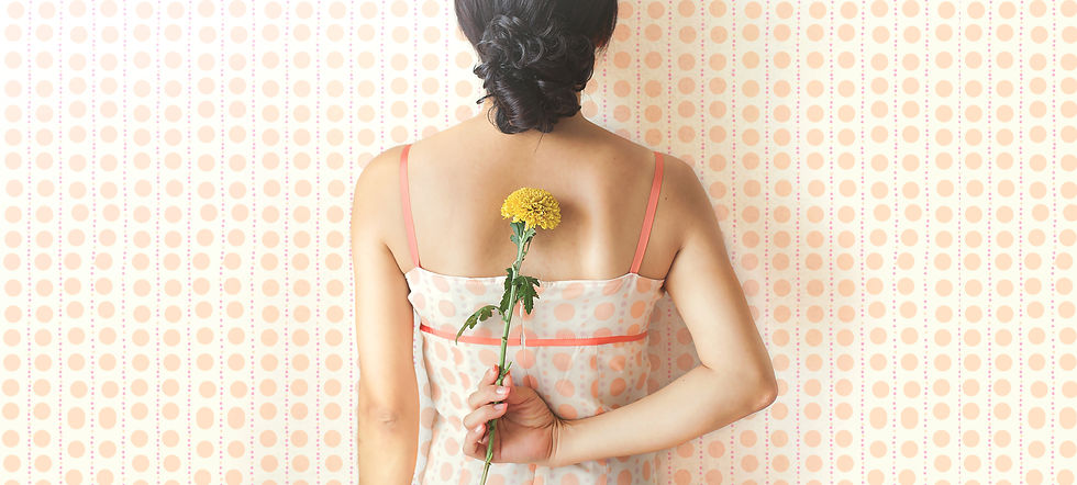 eine Frau von hinten, die eine Blume hinter ihrem Rücken hält