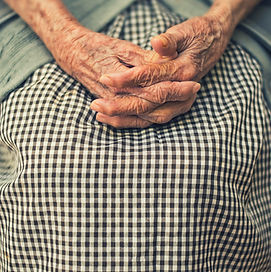 An old woman's hands clasped together in prayer
