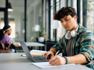 International student using a laptop in a university corridor
