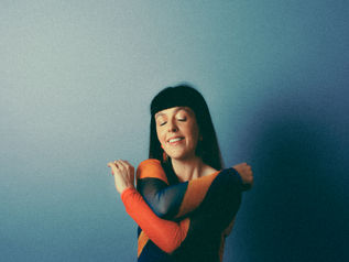 Musician Ria Moran in a colourful top with her eyes close, smiling