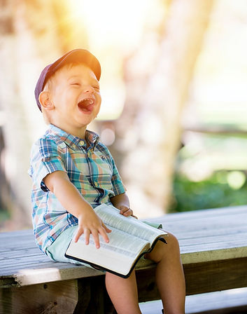 Lachender kleiner Junge das ein Buch liest - strahlt Lebensfreude aus.
