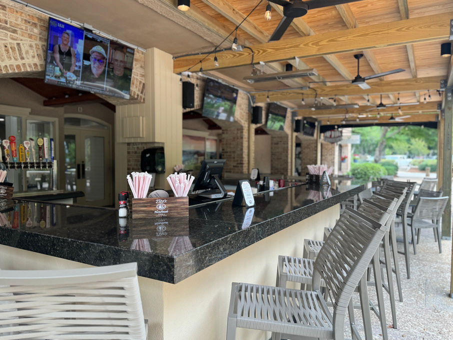 long open air bar with seating and tvs at the tavern